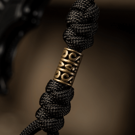 Detaljbilde av M-Tac Zeus Lanyard med flettet paracord og dekorativt messingstykke, perfekt for kniv og utstyr.
