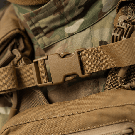 Nærbilde av M-Tac ryggsekk Sturm Elite Gen.II med robust spenne og kamuflasjebakgrunn, ideell for taktiske aktiviteter.