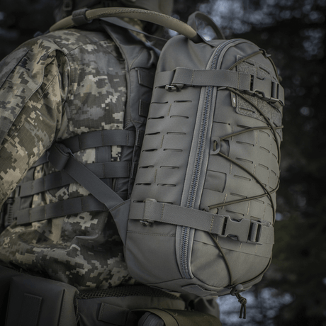 M-Tac ryggsekk Sturm Elite Gen.II båret av en person i militært utstyr, grå, utstyrt med MOLLE-system og elastisk snøring.