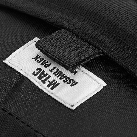 M-Tac Assault Pack Laser Cut-label på en svart ryggsekk med MOLLE-system, perfekt for bybruk og korte fotturer.