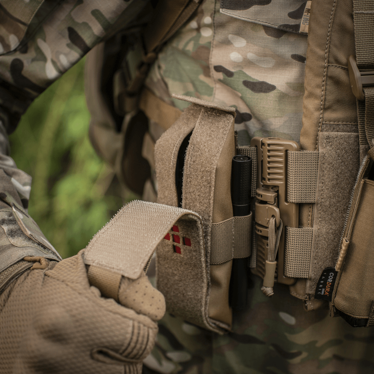 Soldat med M-Tac Lomme til Tourniquet Closed fastgjort til camouflageudstyr til taktisk førstehjælp i felten.