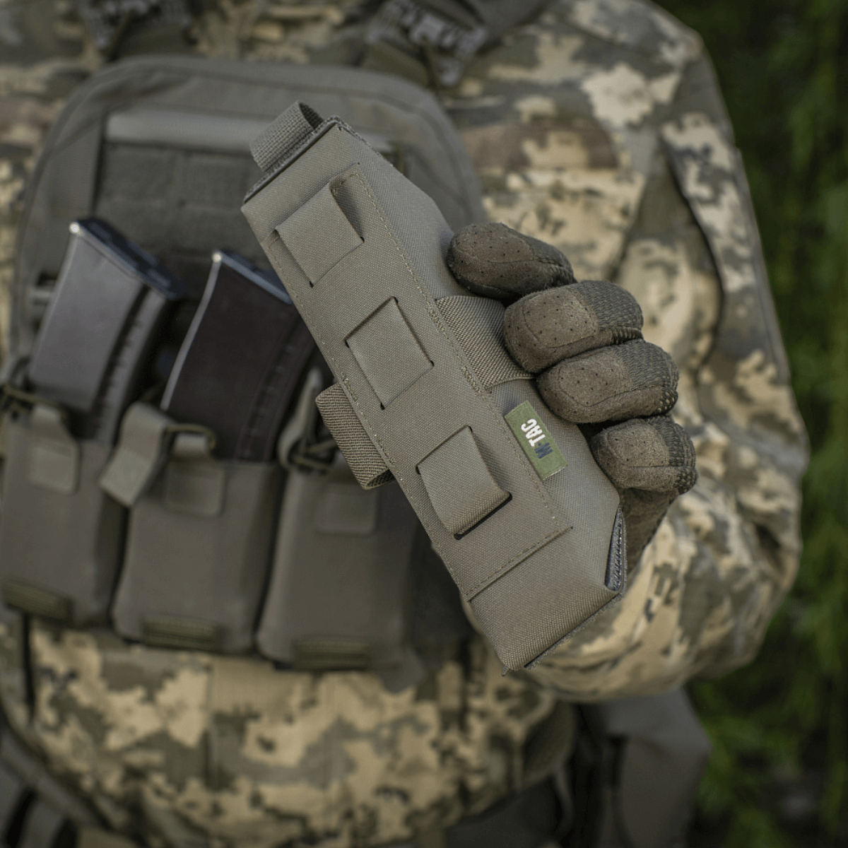 Militærholder viser M-Tac Lomme til Tourniquet Closed fastgjort på uniform i feltmiljø.