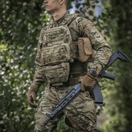Person i kamuflasjeuniform bærer M-Tac Admin Pouch Large Elite og holder et taktisk gevær i en skog.