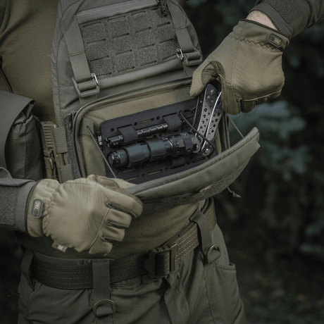 Person åpner M-Tac Admin Pouch Large Elite med taktisk utstyr, laget av slitesterkt Cordura 500D, egnet for utendørs bruk.