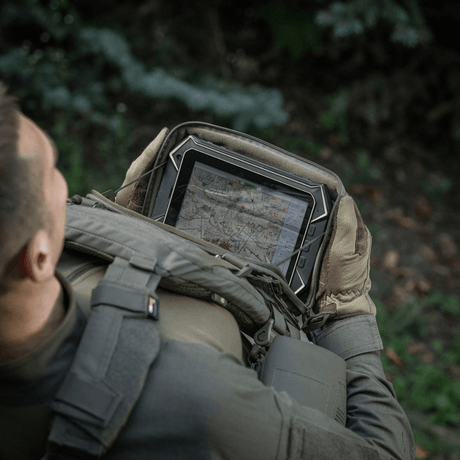 Person med M-Tac Admin Pouch Large Elite holder et nettbrett i en skog.