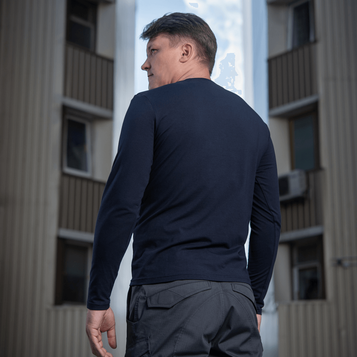 M-Tac Long-sleeve T-shirt 93/7 i mørkblå, set bagfra på en mand i et bymiljø.