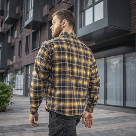 Mand iført M-Tac Redneck Skjorte i Navy Blue/Yellow med velcro-justerbare ærmer og forstærkede skuldre i bymiljø.