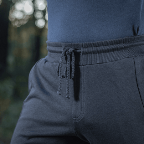 Person iført M-Tac Bukser Stealth Cotton med elastik i taljen og sidelommer, lavet af 100% bomuld for komfort og bevægelsesfrihed.