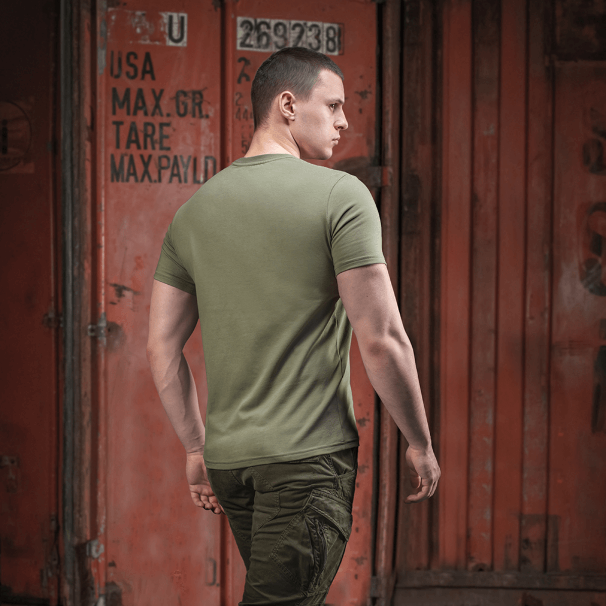 Mand i M-Tac T-shirt Viking foran container, set bagfra, militærgrøn stil