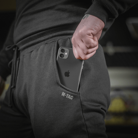 Person iført M-Tac Bukser Cotton Classic med smartphone i sidelomme, sportstøj i 100% bomuld med komfort og bevægelsesfrihed.