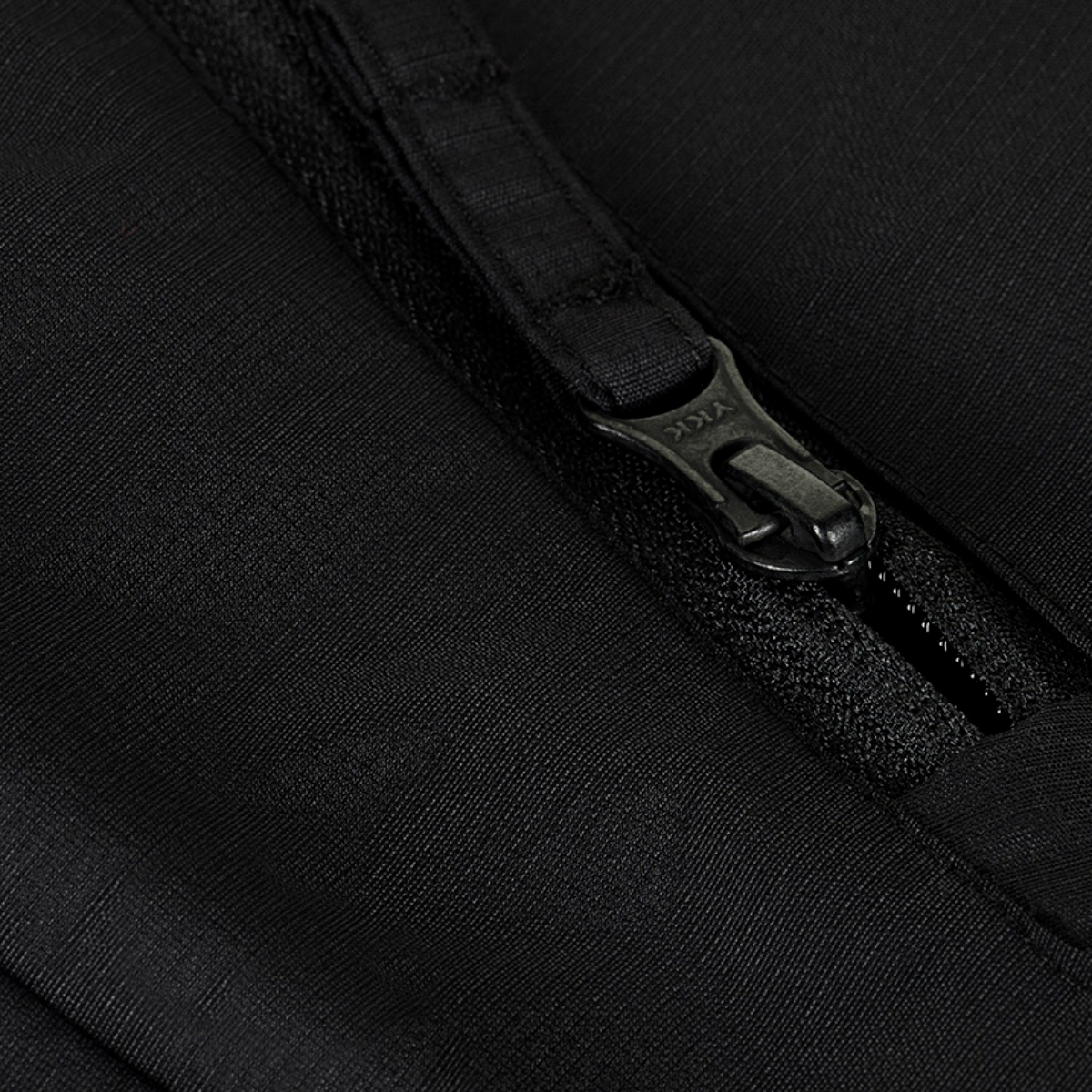 Nærbillede af lynlås på M-Tac Alpha Gen.III Pro Vinterjakke, fremviser holdbar sort vandtæt nylonmateriale.