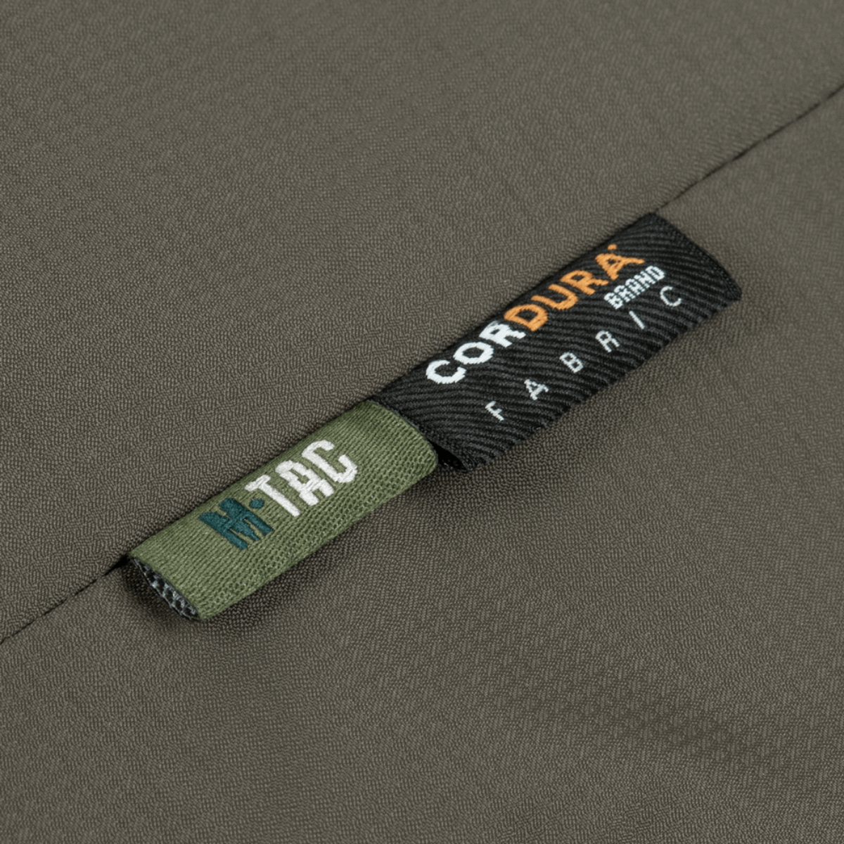 Close-up af M-Tac Alpha Gen.III Pro Vinterjakke med Cordura stofmærke, der fremhæver holdbarhed og kvalitet.