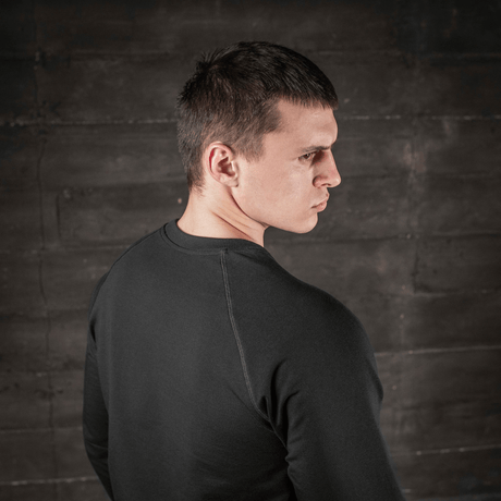 Mann iført M-Tac Raglan Athlete svart sweatshirt med raglanermer, sett bakfra, ideell for sport og hverdag.