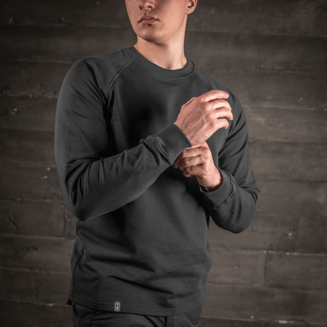 Mann iført M-Tac Raglan Athlete-sweatshirt med rund hals og raglanermer i svart, ideell for sport og hverdag.
