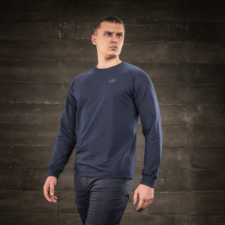 M-Tac Raglan Athlete-sweatshirt i minimalistisk design med raglanermer, vist på modell mot en rustikk bakgrunn.