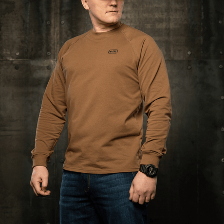 M-Tac Raglan Athlete-sweatshirt med rund hals og raglanermer i coyote, ideell for sport og daglig bruk, sett i en industriell setting.