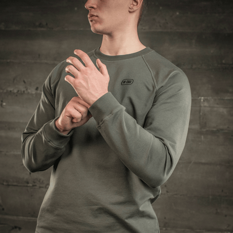 M-Tac Raglan Athlete sweatshirt med raglanerm i olivenfarge, designet for allsidig bruk og maksimal bevegelsesfrihet, vist på en person.