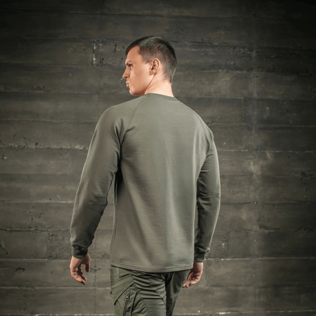 Mann iført M-Tac Raglan Athlete sweatshirt i olivengrønn, sett bakfra med raglanerm for fri bevegelse, perfekt for sport og hverdag.