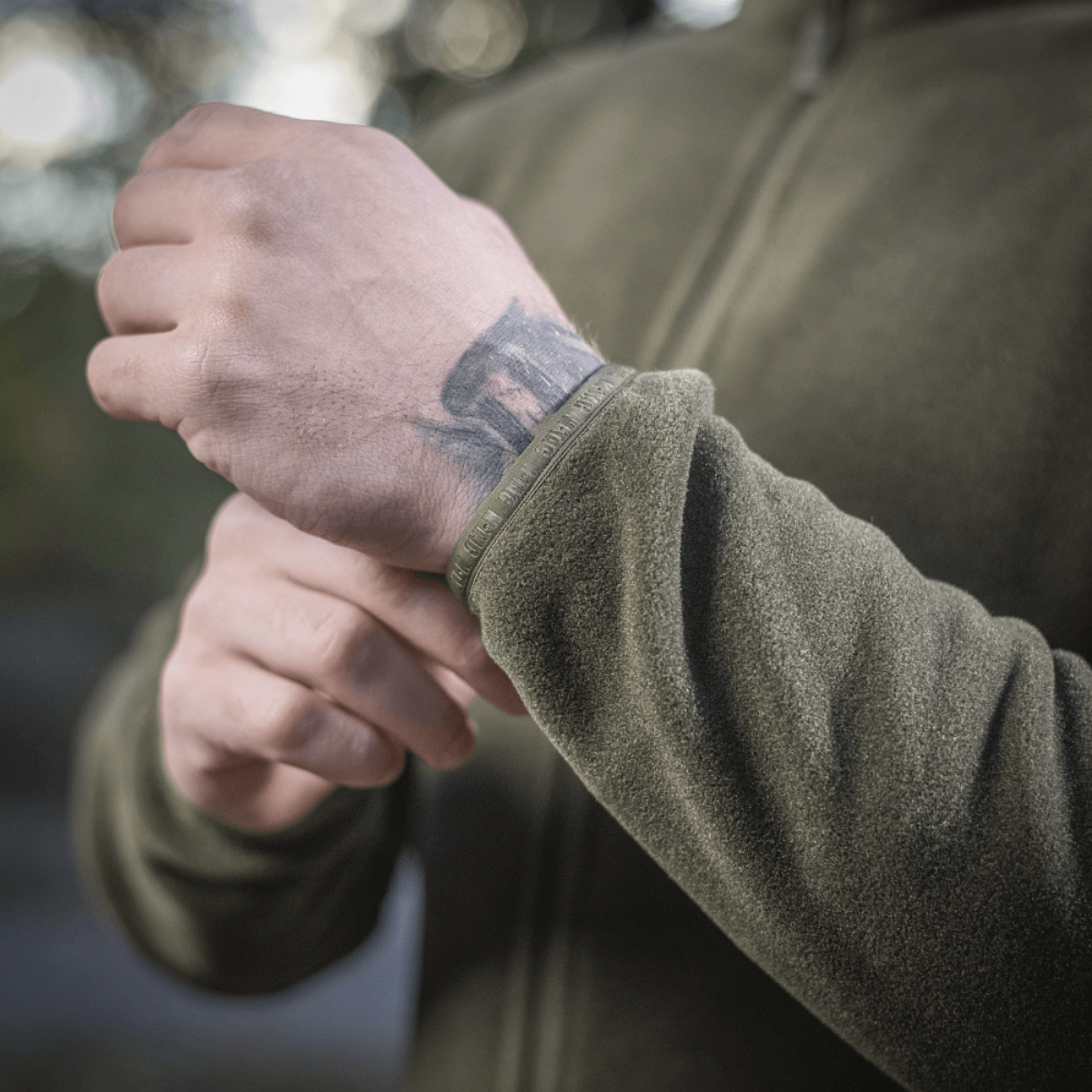 Person iført M-Tac Nord Polartec Fleecejakke justerer ærmet på jakken, lavet af premium Polartec® 200 Series fleece.