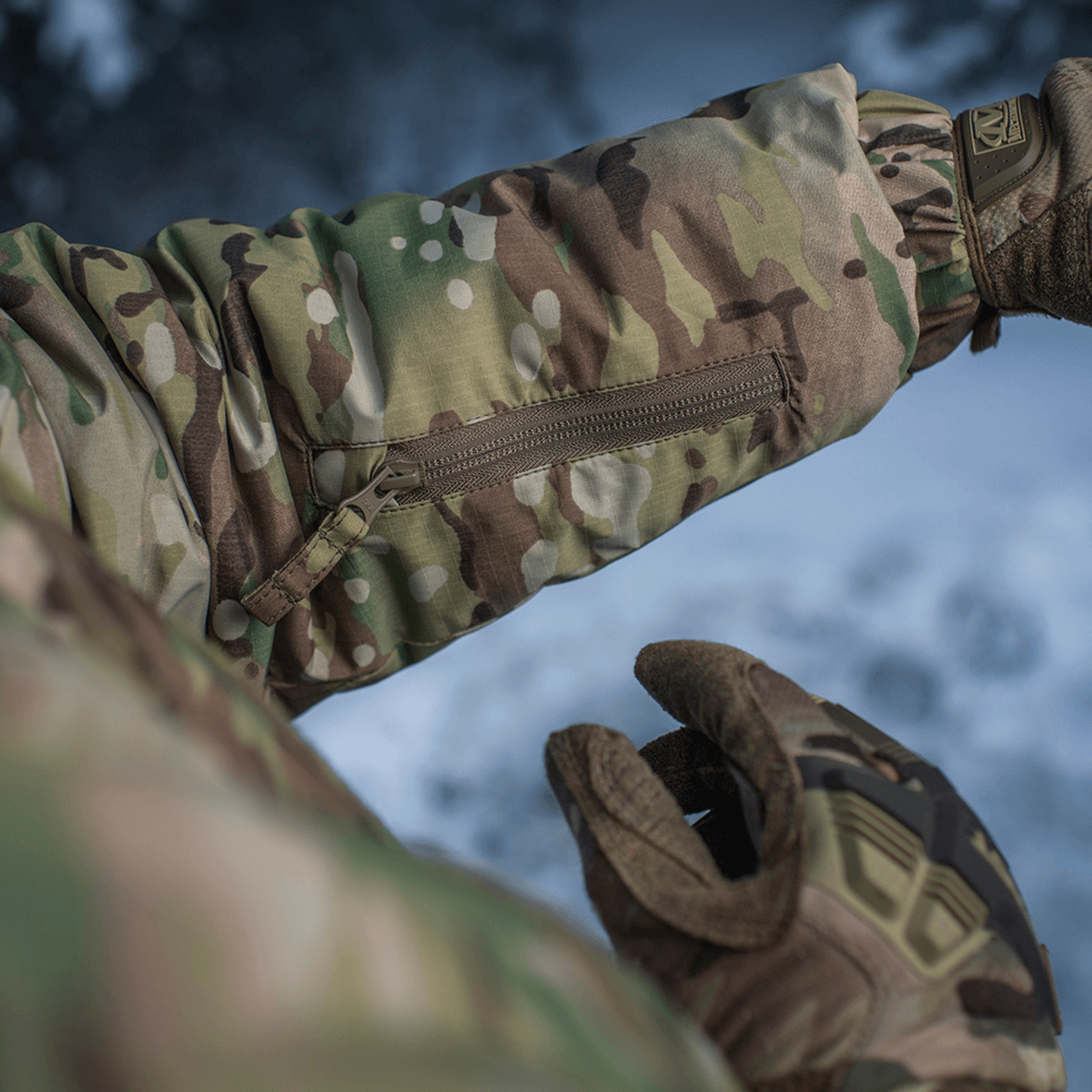 Nærbillede af M-Tac Alpha Gen.IV Pro Primaloft Vinterjakke med Multicam mønster og lynlåslomme.