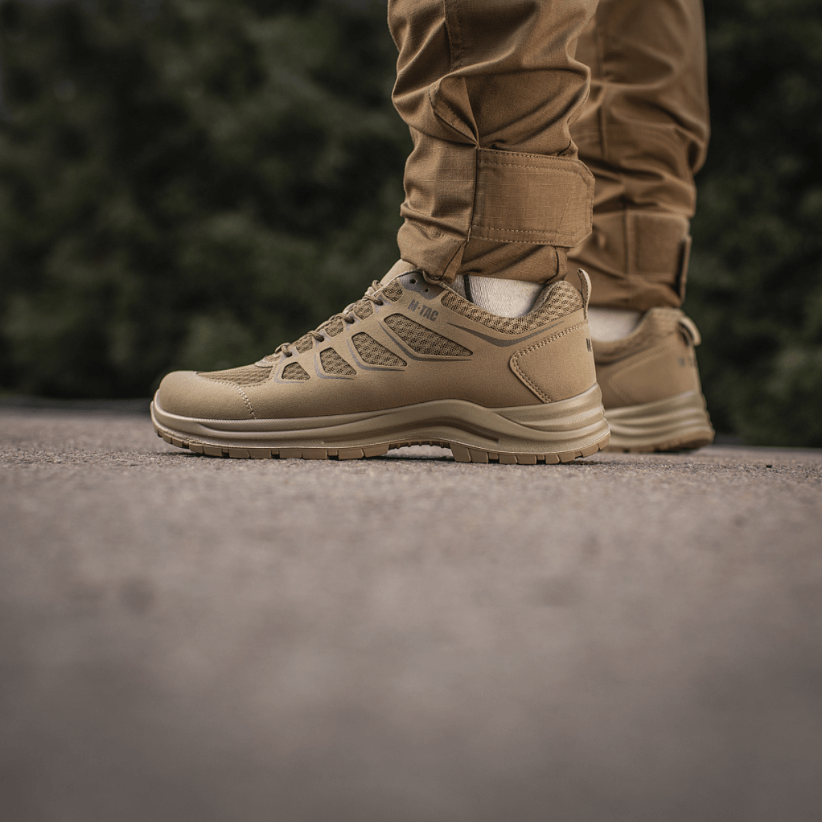 M-Tac Tactical Sneakers IVA på person iført brune bukser, lette og ventilerede sneakers, perfekte til sommeraktiviteter og outdoor-brug.