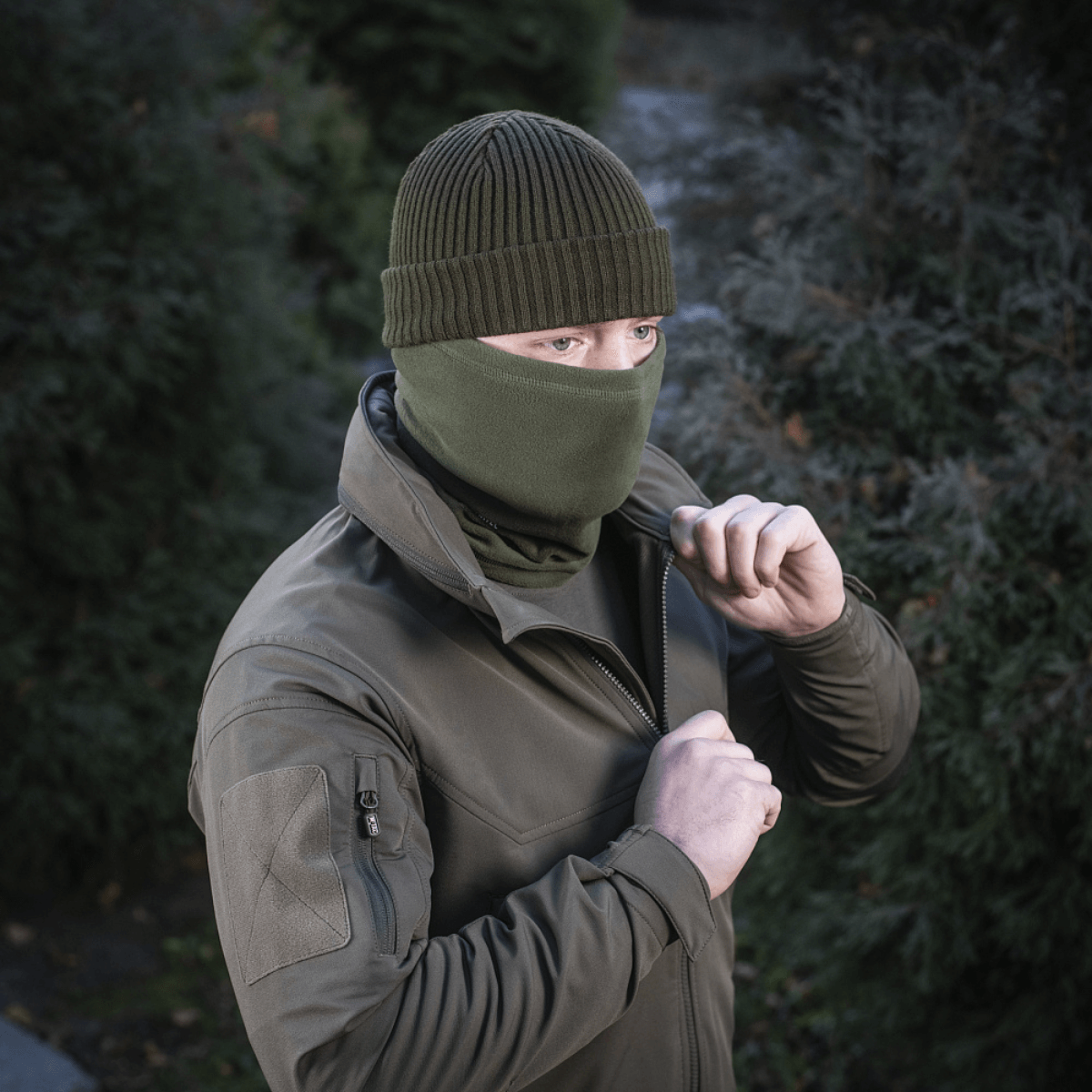 Mand iført M-Tac Tube Scarf Polartec som ansigtsmaske, stående i udendørs miljø, klar til kolde sæsonens aktiviteter.