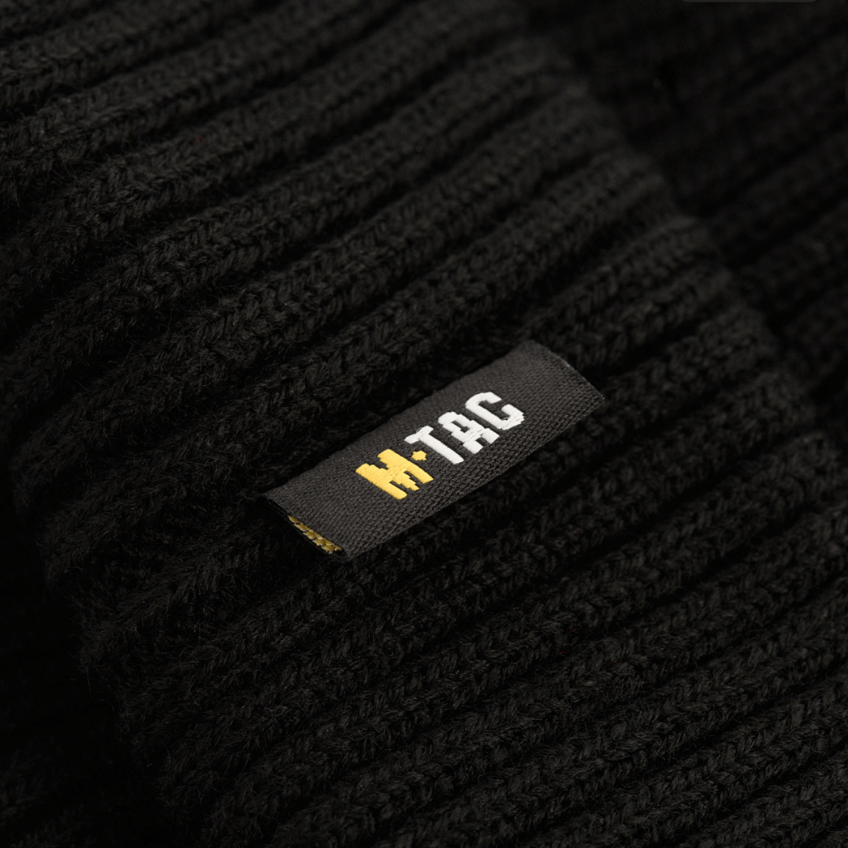 Nærbillede af M-Tac Watch Cap 100% Akryl med sort stof og M-Tac logo, ideel til koldt vejr. Lav profil og industrielt dobbeltstrik.