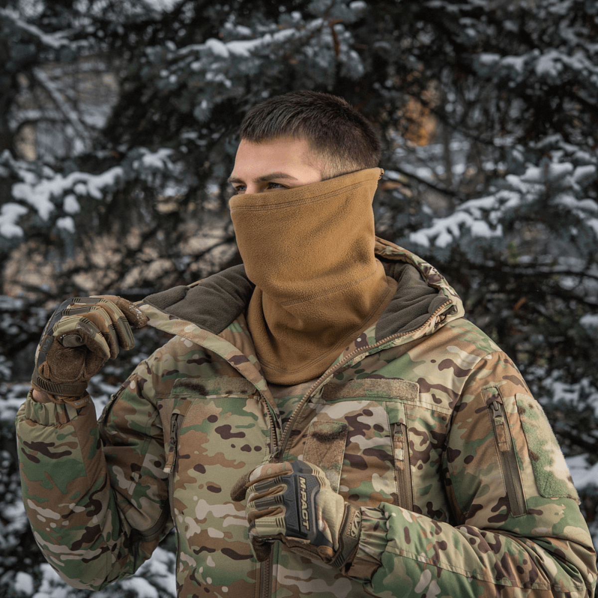 Mand iført M-Tac Anatomisk Snood Justerbar Elite Fleece (320 g/m²) i skovomgivelser, fremviser multifunktionelt design til koldt vejr