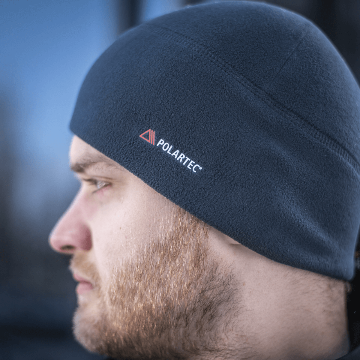 Mand iført M-Tac Fleece Watch Cap Light Polartec, viser den bløde og varme vinterhat med Polartec-logo, perfekt til kulde og vind.
