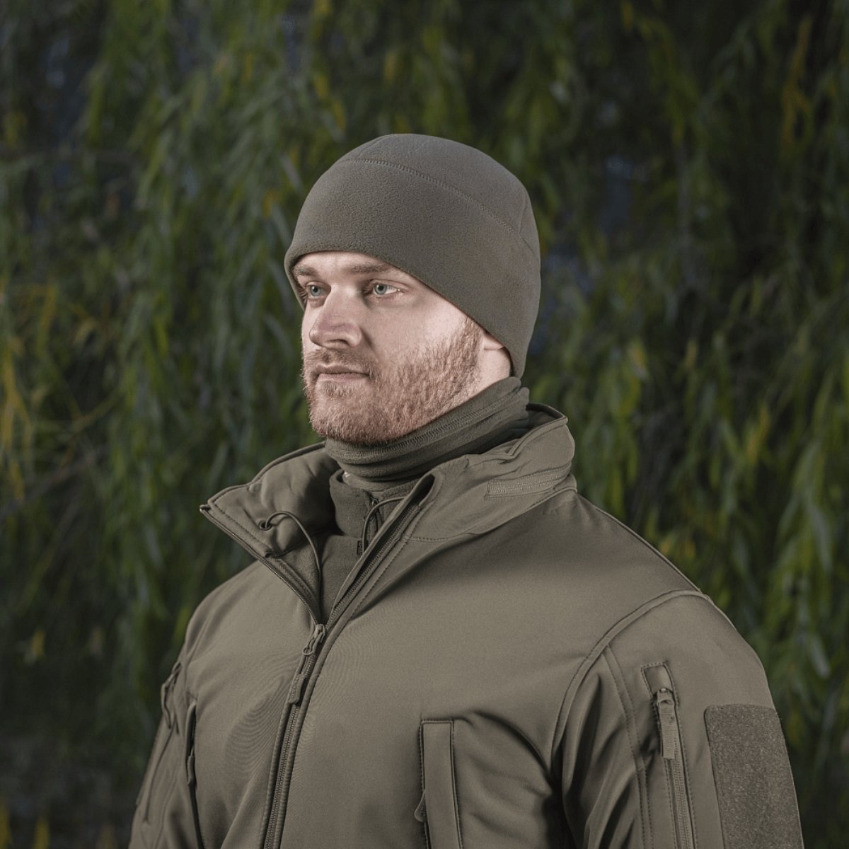 Mand iført M-Tac Fleece Polartec Watch Cap i skovmiljø, velegnet til udendørs aktiviteter og vinterbrug