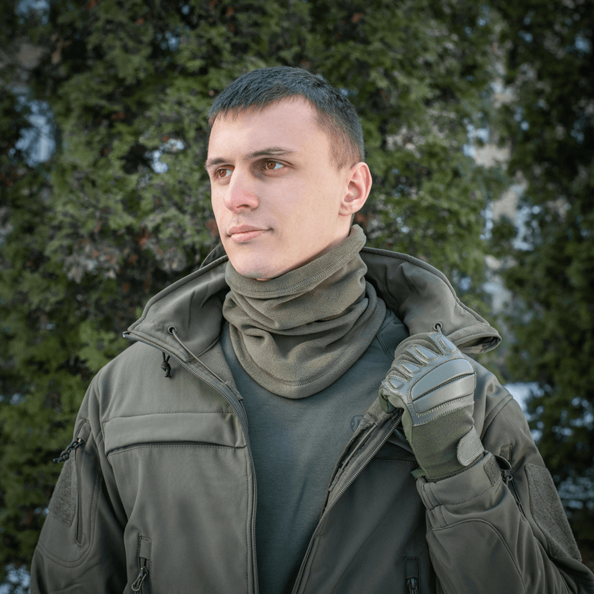 En mand iført M-Tac Polartec Anatomic Tube Scarf i et skovområde, ideel til beskyttelse mod kulde og vind.