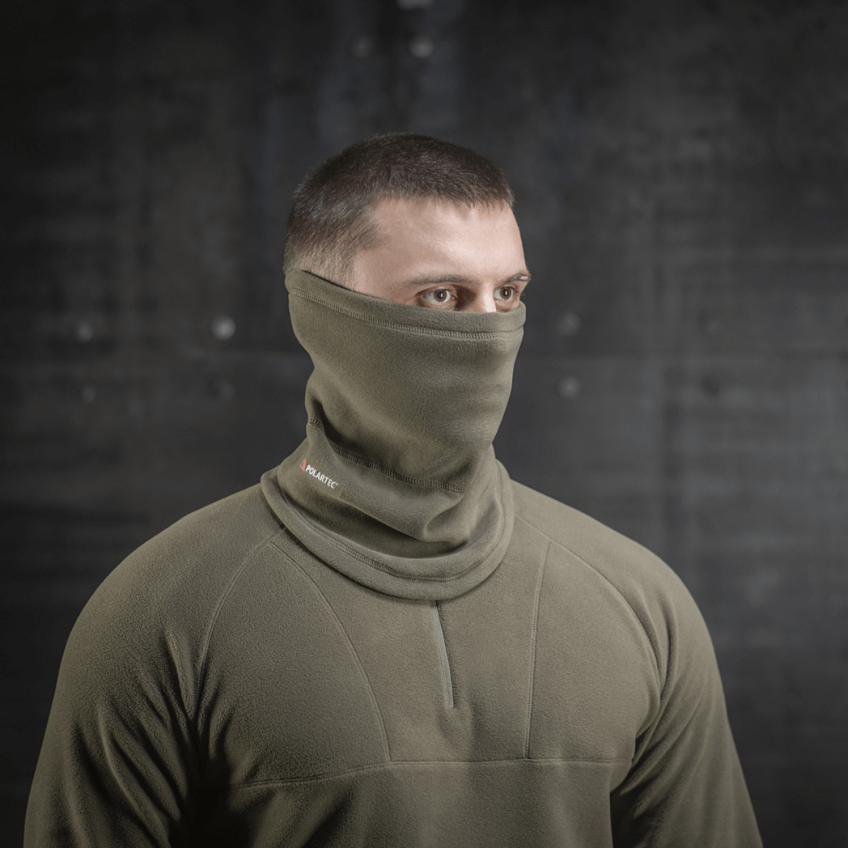 Mand med M-Tac Polartec Anatomic Tube Scarf i olivengrøn, multifunktionelt tørklæde, der beskytter mod vind og kulde.