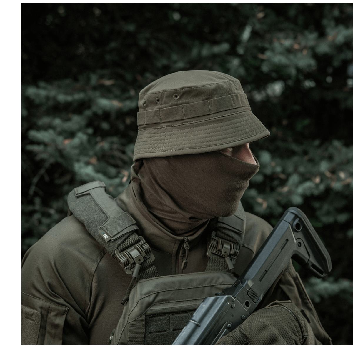 Militærperson iført M-Tac Panamahat Gen. II Summer Flex i skovmiljø, viser solbeskyttelse og komfort til varme sæsoner.