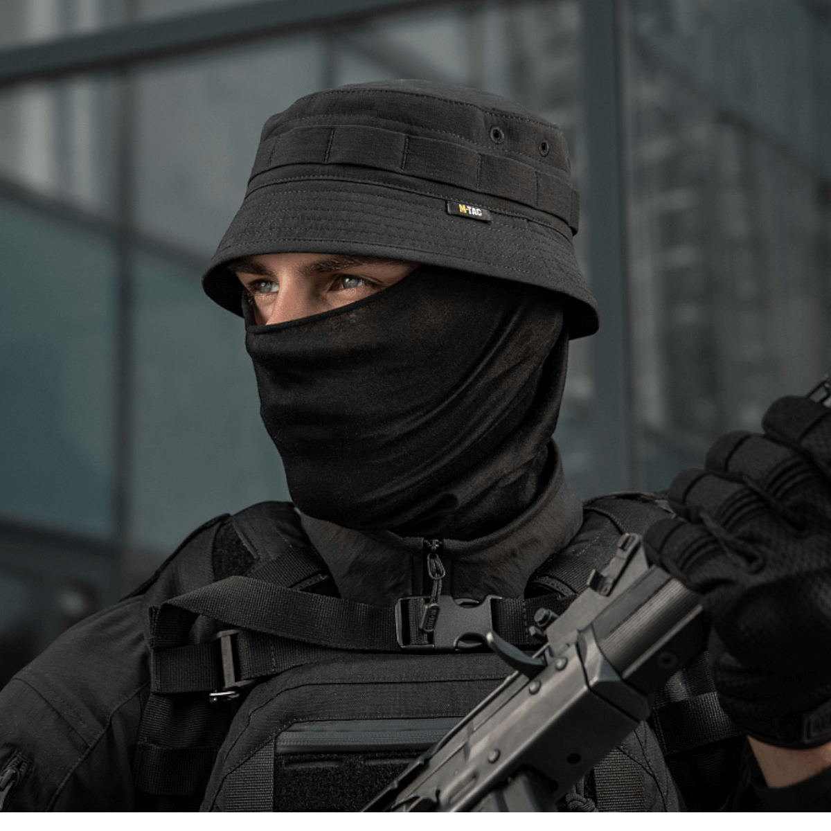 M-Tac Panamahat Gen. II Summer Flex i sort, bæres af en person i taktisk tøj, ideel til beskyttelse i solfyldte omgivelser.