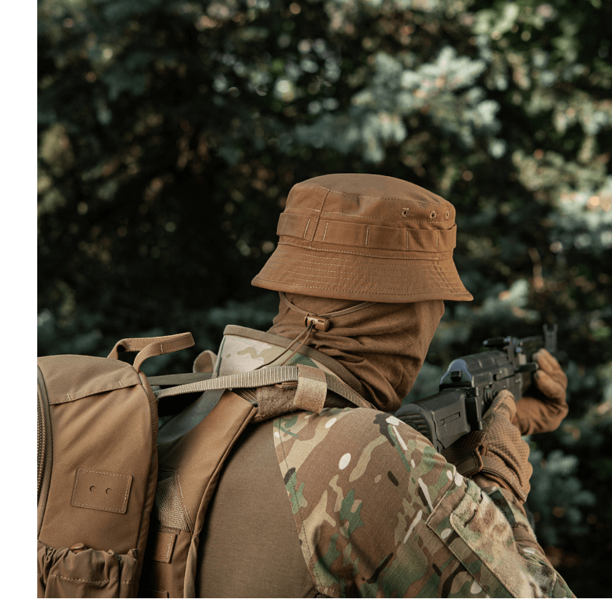 En person i camouflage med M-Tac Panamahat Gen. II Flex Rip-Stop i skovmiljø