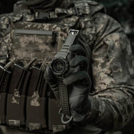 M-Tac Tactical Ur med Kompass 2233 holdt av taktisk kledd person, viser robust urdesign egnet for utendørs og daglig bruk.