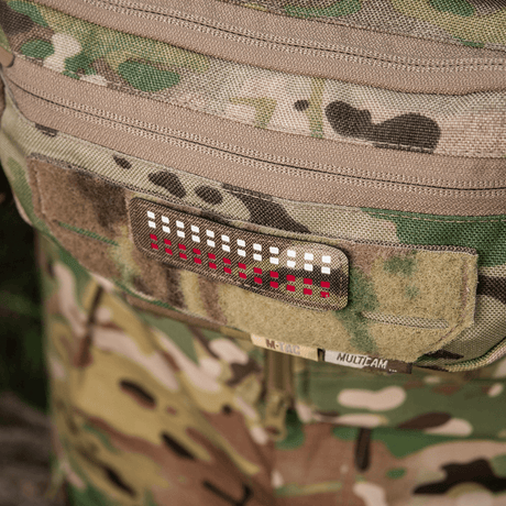 M-Tac Patch Flag 25x80 Mini Squares med Laser Cut-design på bekledning av Cordura 500D med velcrofeste, kamuflasjebakgrunn.