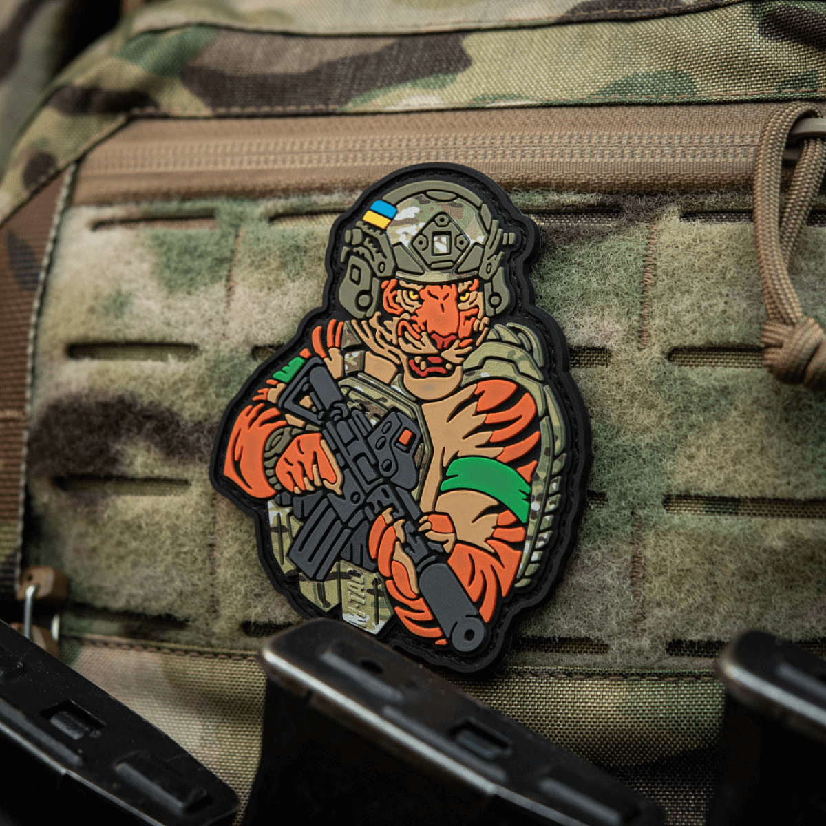 Alt tag: M-Tac Patch Tiger Green Tape PVC - 3D patch af tiger med AR-15, hjelm og QRS plate carrier på camouflageret udstyr.