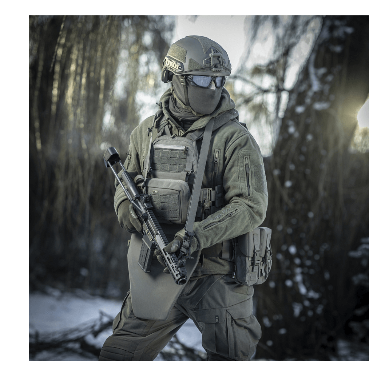 Person udstyret med M-Tac Universal Våbenrem i en skov, klar til taktisk brug. Perfekt til både to-punkts og enkeltpunkts fastgørelse.