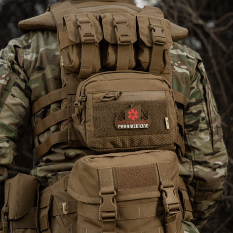 Taktisk ryggsekk med 'Paramedicine'-patch i camouflagemønster sett bakfra i naturen, robust og holdbar for utendørs bruk.