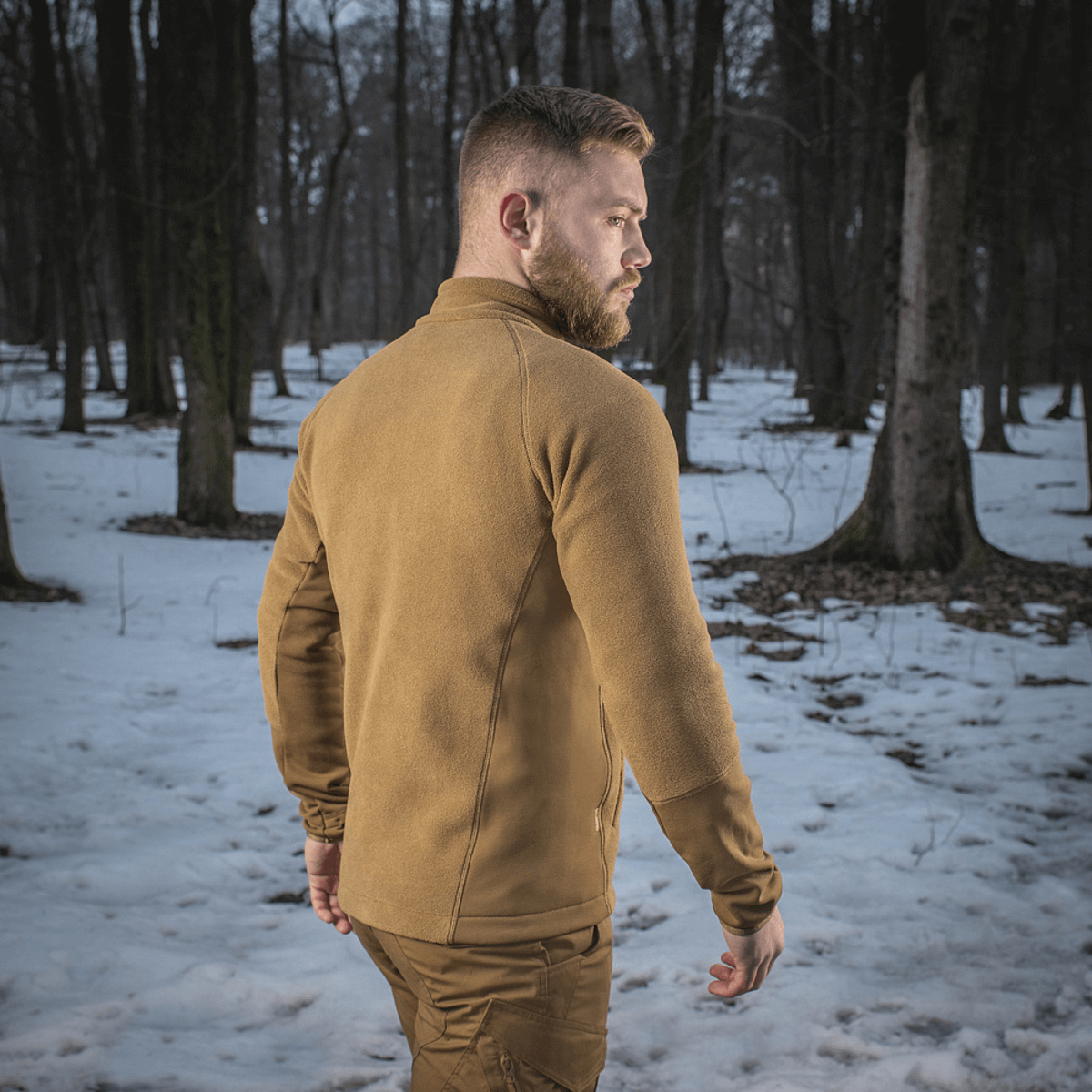 M-Tac Polartec Sport Fleecejakke i en sneklædt skov, perfekt som yderlag eller mellemlag for varme og komfort.