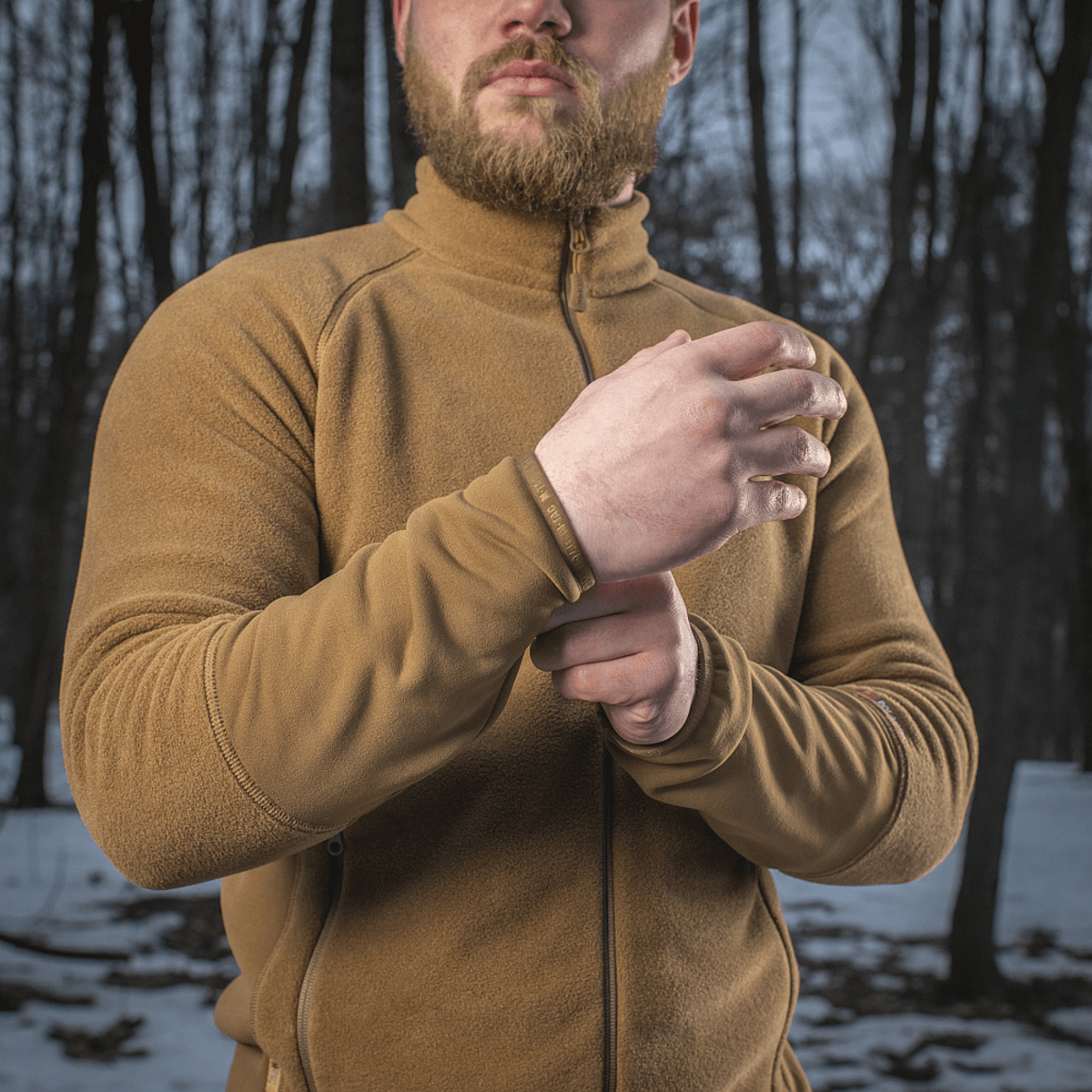 Mand iført M-Tac Polartec Sport Fleecejakke i en skov, understregende varmeisolering og komfort for både overgangs- og vinterperioder.