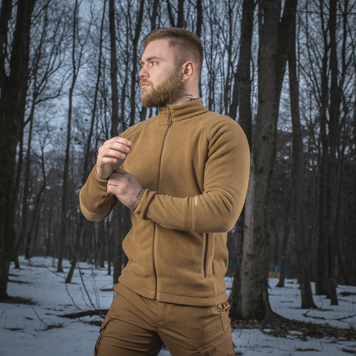 Mand iført M-Tac Polartec Sport Fleecejakke i en sneklædt skov baggrund