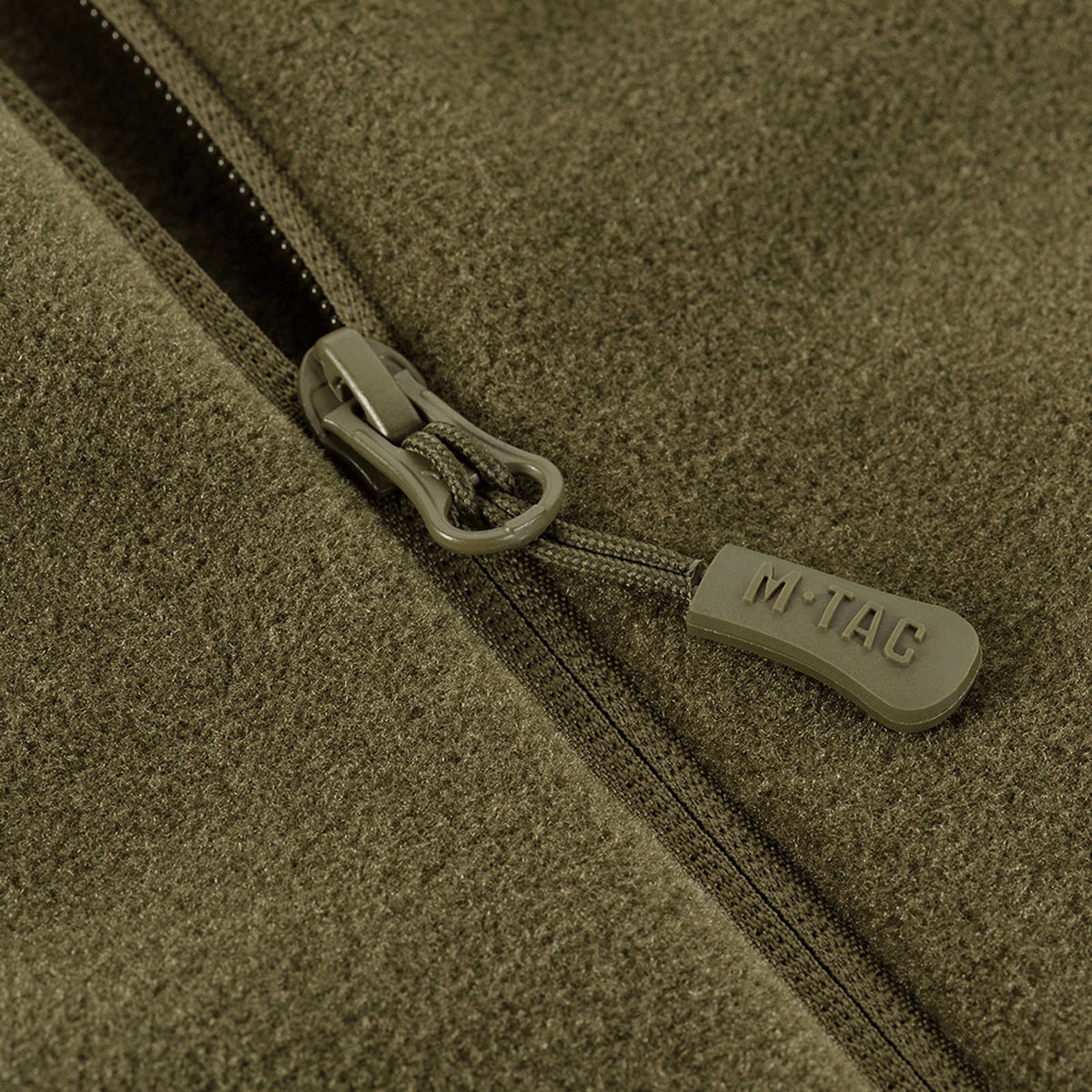 Nærbillede af lynlås på M-Tac Polartec Sport Fleecejakke i olivengrøn farve, der viser premium Polartec® 200 Series fleece materiale.