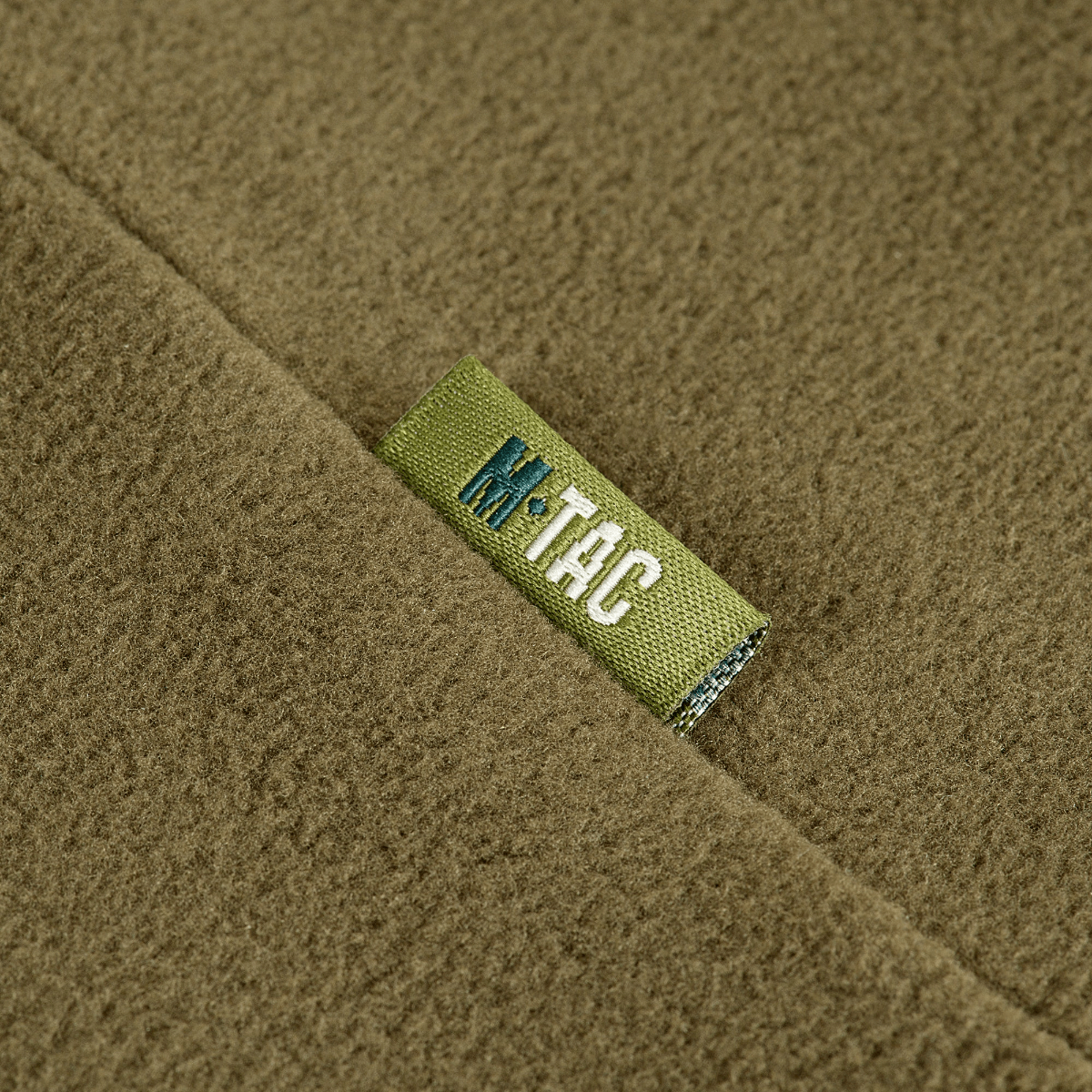 Nærbillede af M-Tac Delta Polartec Pullover Dame i olivengrøn farve med mærkelabel.