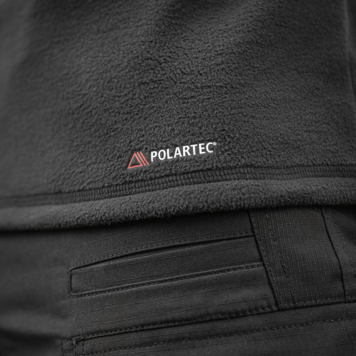 Detalje af M-Tac Delta Polartec Raglan Jakke lavet af Polartec fleece med Polartec logo.