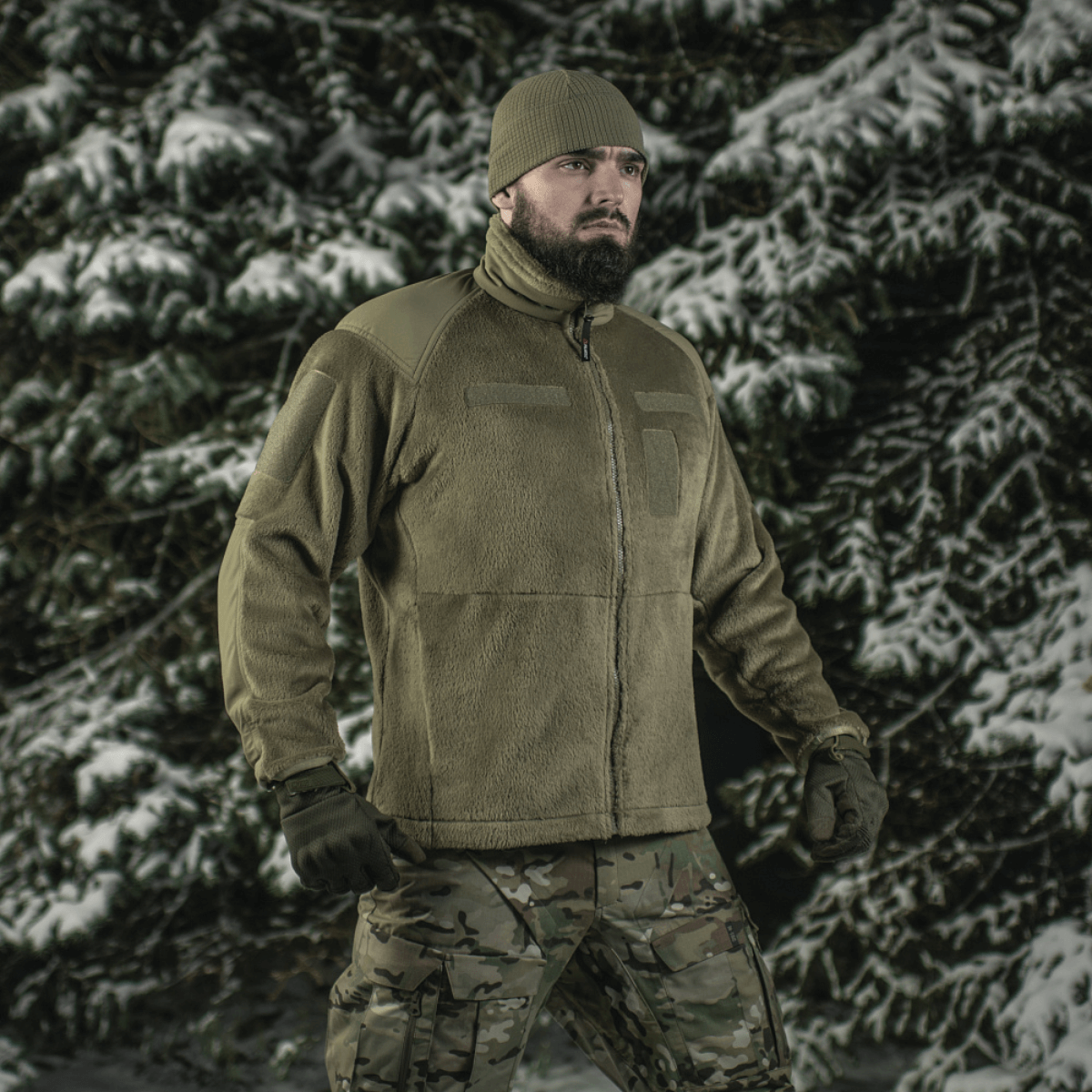 Mand i skov bærer M-Tac Battle Fleece Polartec Jakke, perfekt til militær og politi, fremhæver komfort og holdbarhed i vinterlandskab.