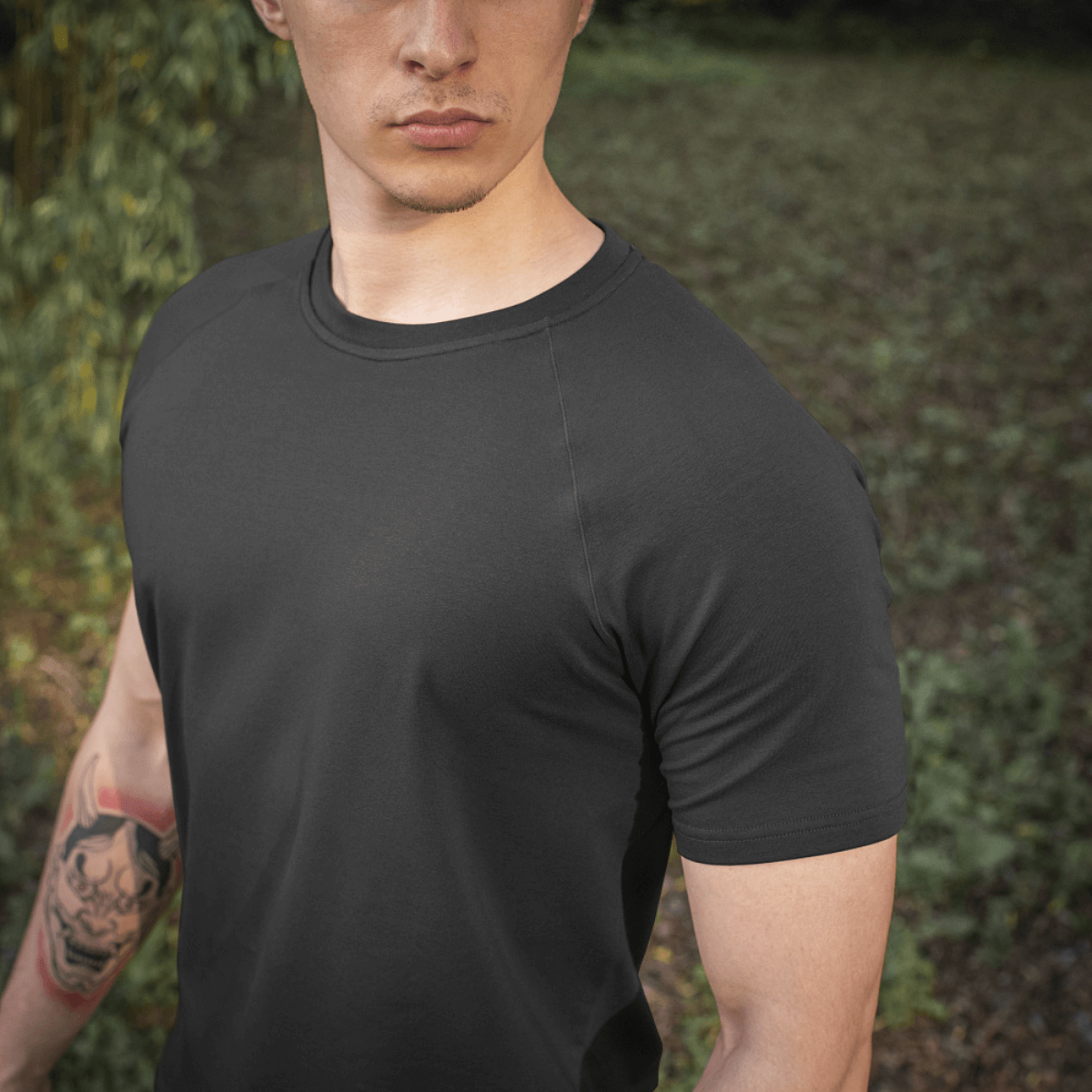 Mand iført M-Tac Raglan T-Shirt 93/7 for optimal komfort og bevægelsesfrihed i sort med raglanærmer i naturligt miljø