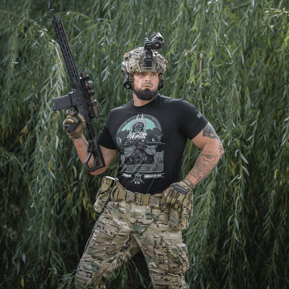 M-Tac T-Shirt Odin Mystery med print af Odin fra nordisk mytologi, båret af en person i militærudstyr foran en skovbaggrund.