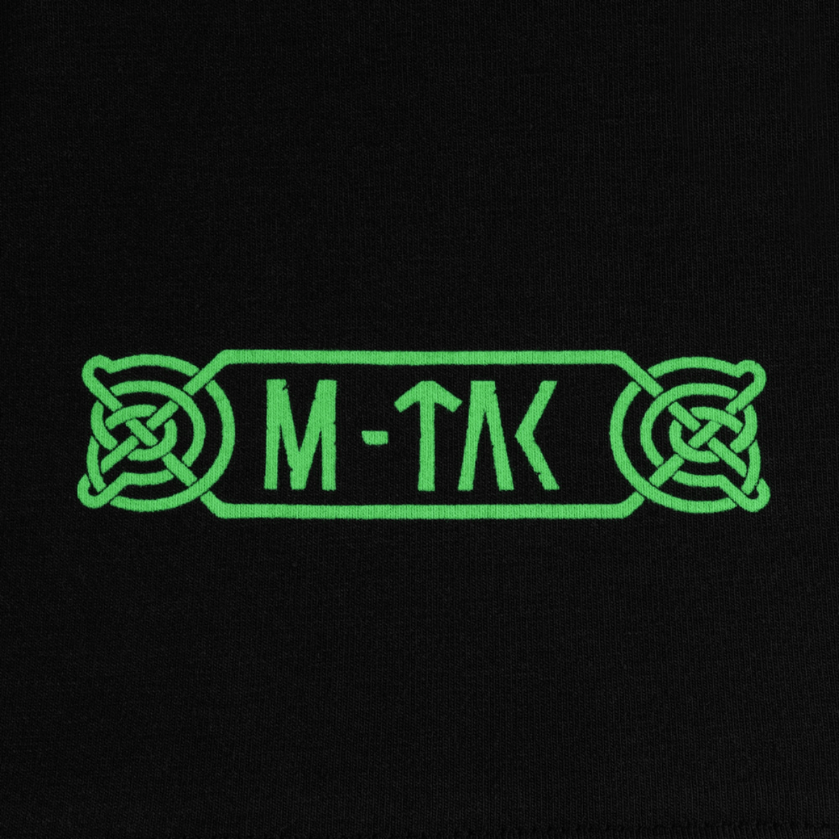 Nærbillede af M-Tac T-Shirt Night Vision logo i grøn nordisk stil, inspireret af Odins mytologi, på en sort baggrund.